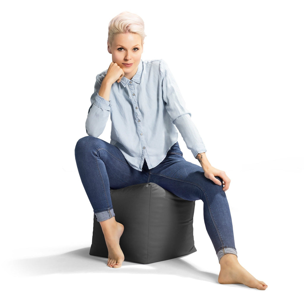 Woman sitting on a black bean bag chair against a white background