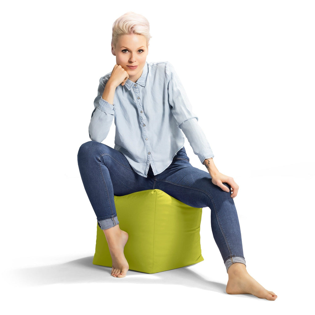 Woman sitting on a green bean bag chair against a white background