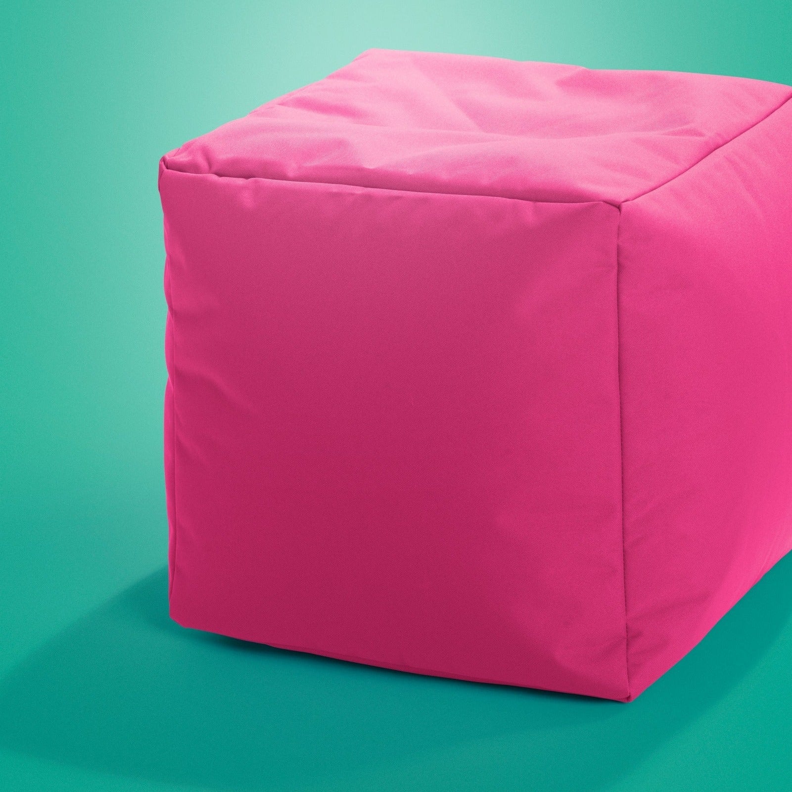 Pink cube-shaped ottoman on a teal background