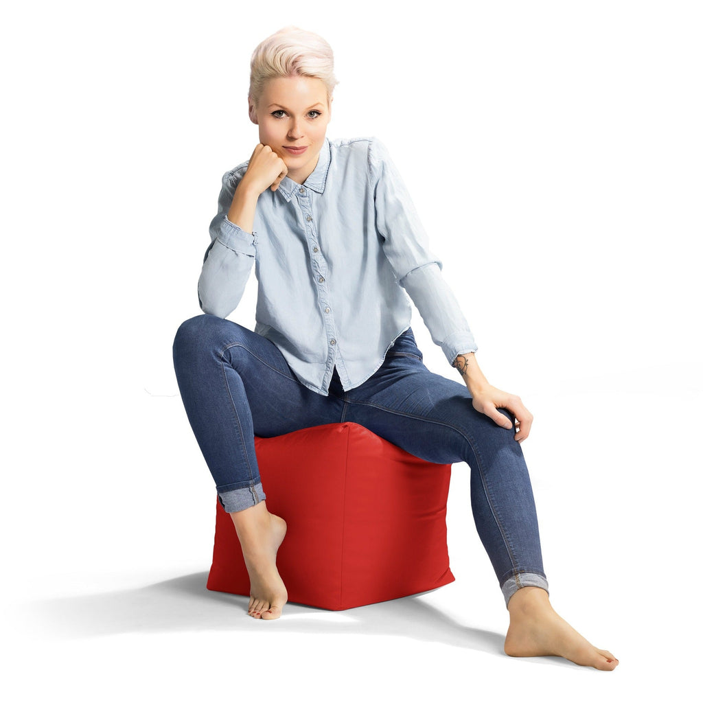 Woman sitting on a red bean bag chair against a white background