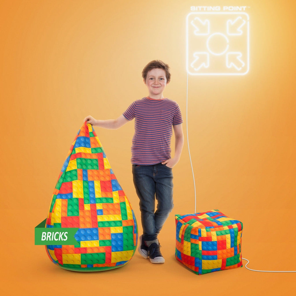 Child standing next to a colorful bean bag and cube with 'BRICKS' branding on an orange background.