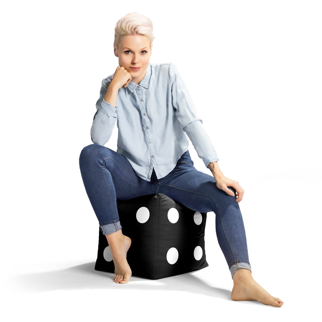 Woman sitting on a black ottoman with white polka dots against a white background