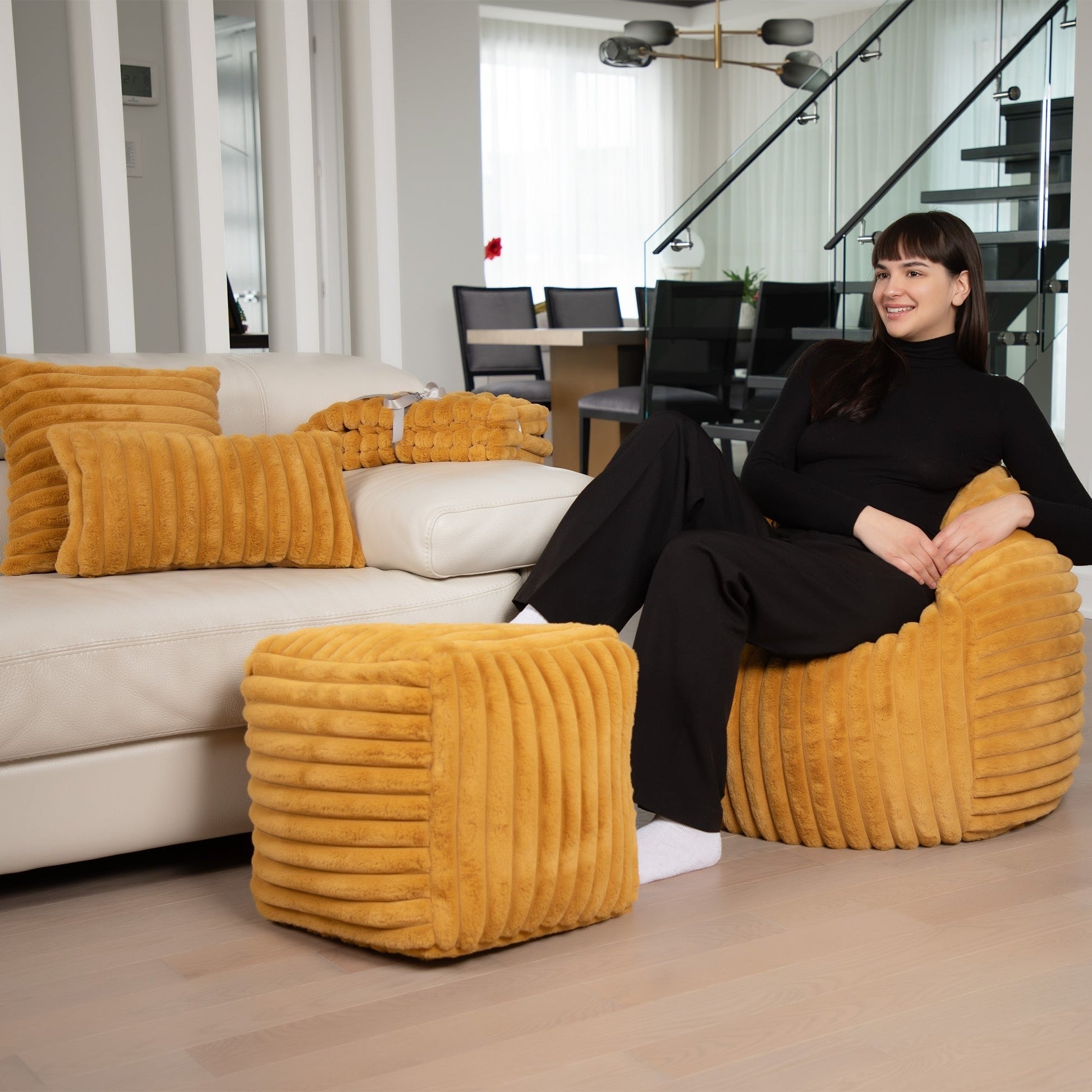 Woman sitting on a yellow textured chair in a modern living room.