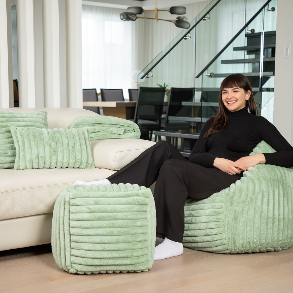 Woman sitting on a green textured chair in a modern living room.