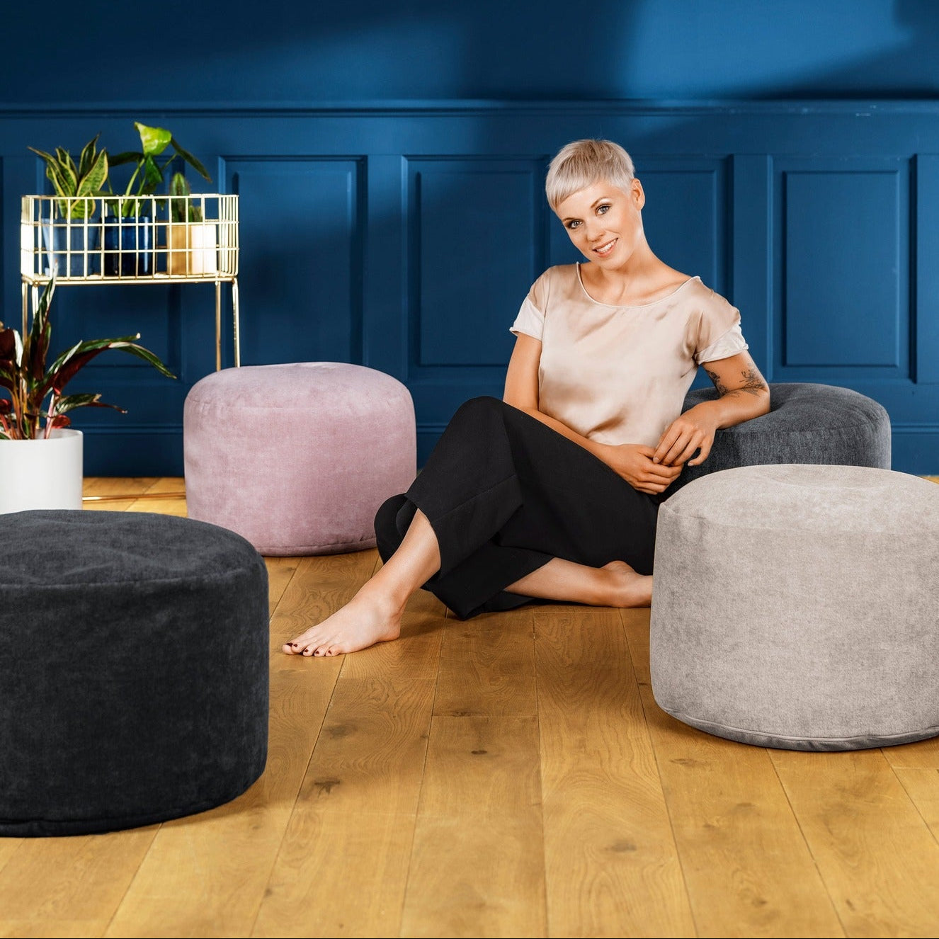 Woman sitting on a gray chair in a room with blue walls and various ottomans.