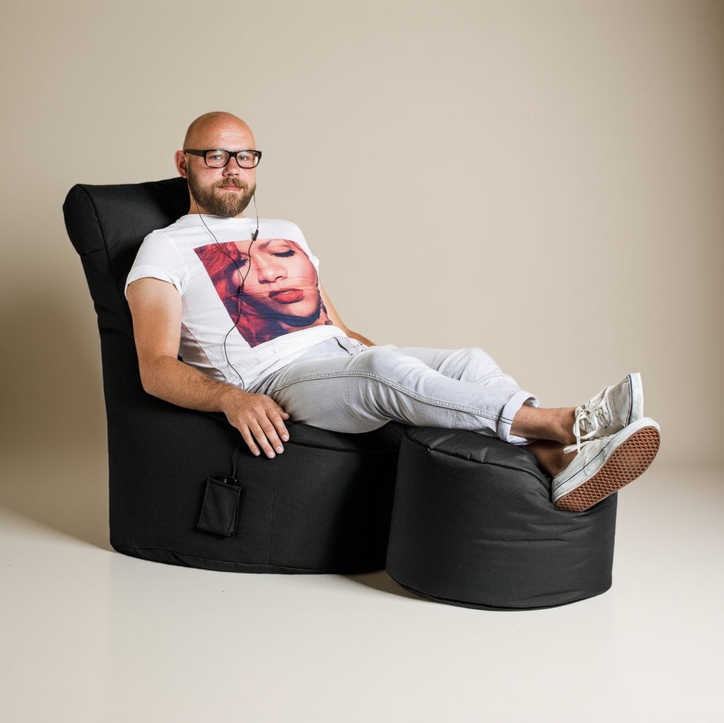 Man sitting on a black bean bag chair with a white background
