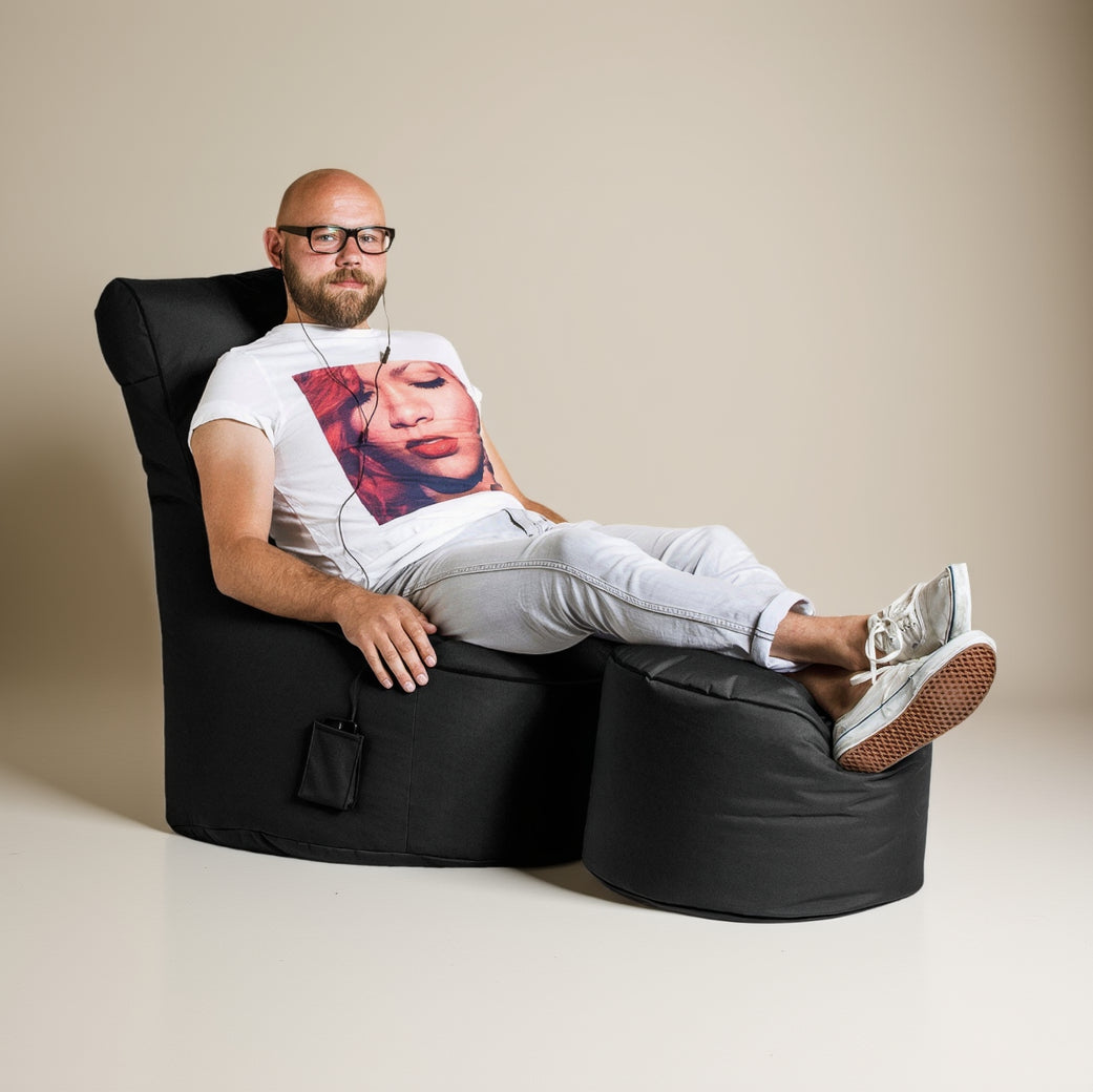 Man sitting on a black bean bag chair with a white background