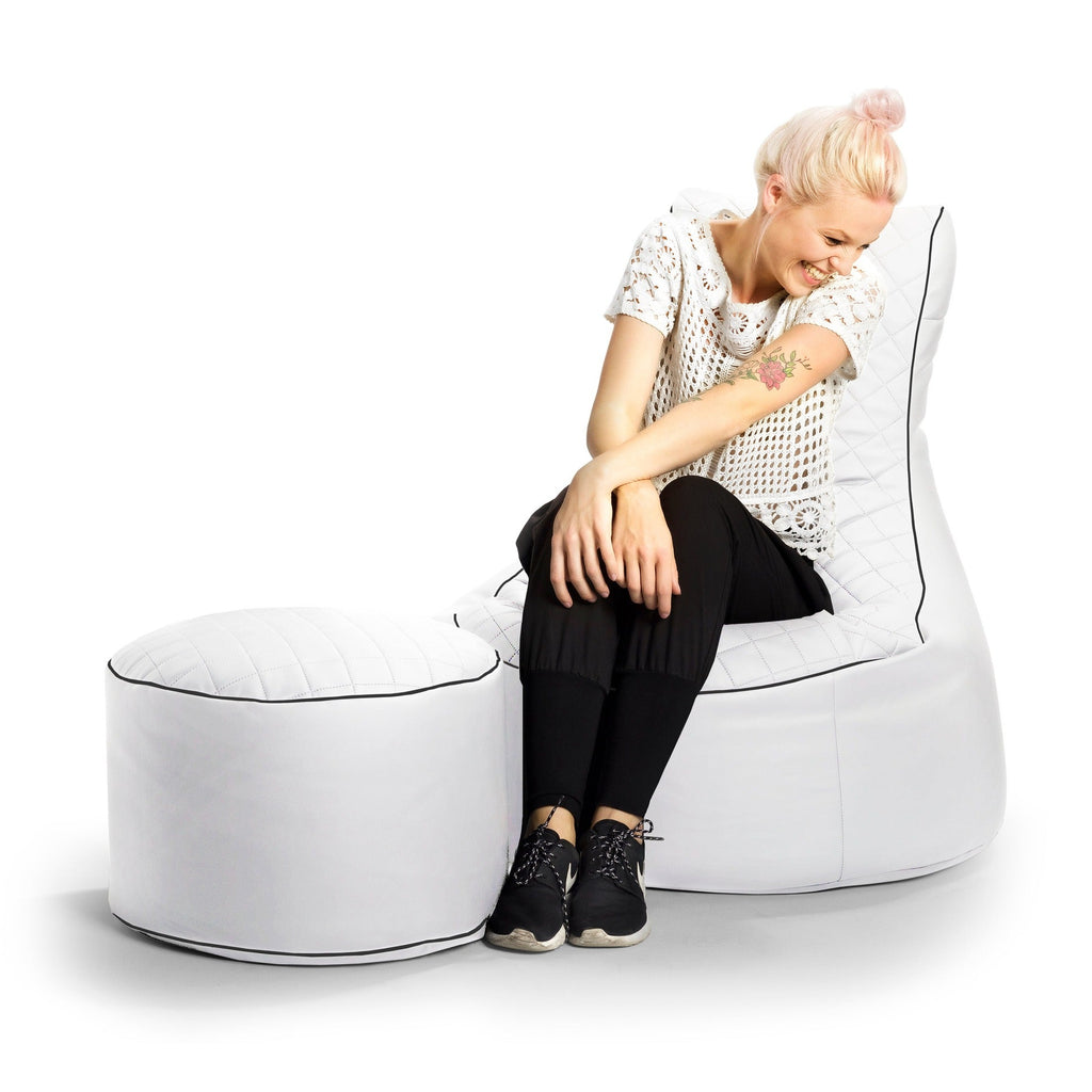 Woman sitting on a modern white chair with a matching ottoman on a white background