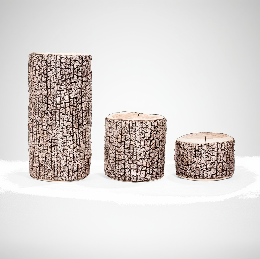 Three cylindrical candles with bark-like texture on a white background