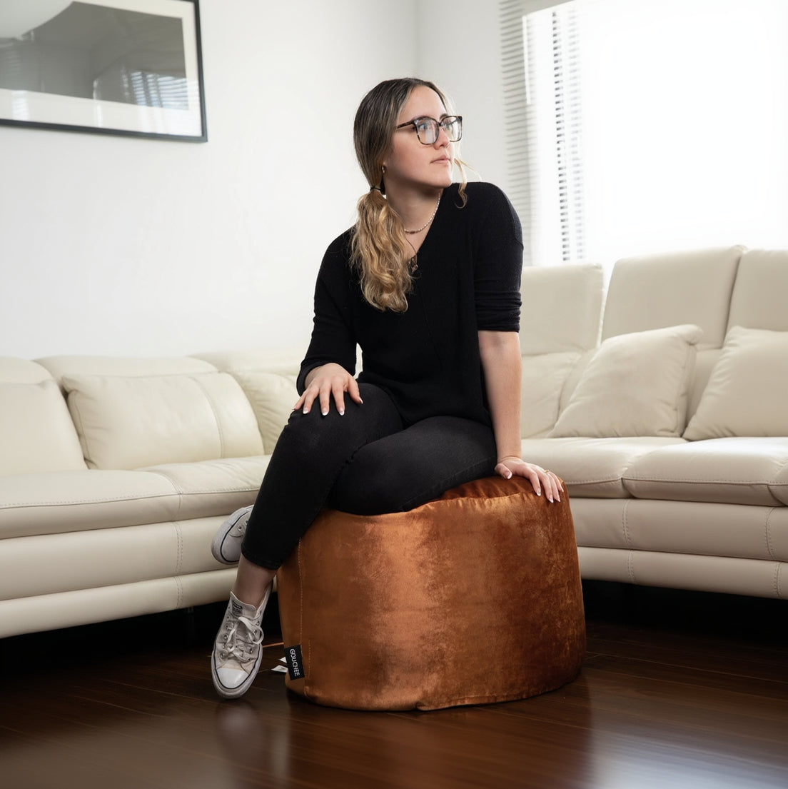 Woman sitting on a brown bean bag chair in a living room.