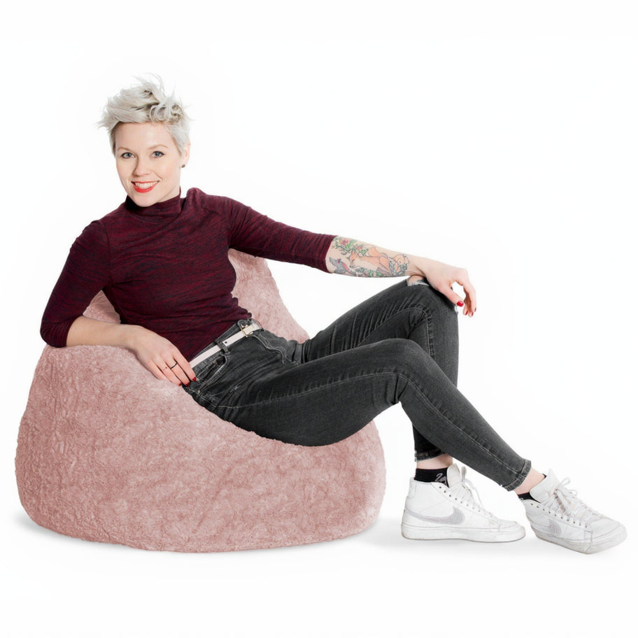 Woman sitting on a pink bean bag chair against a white background