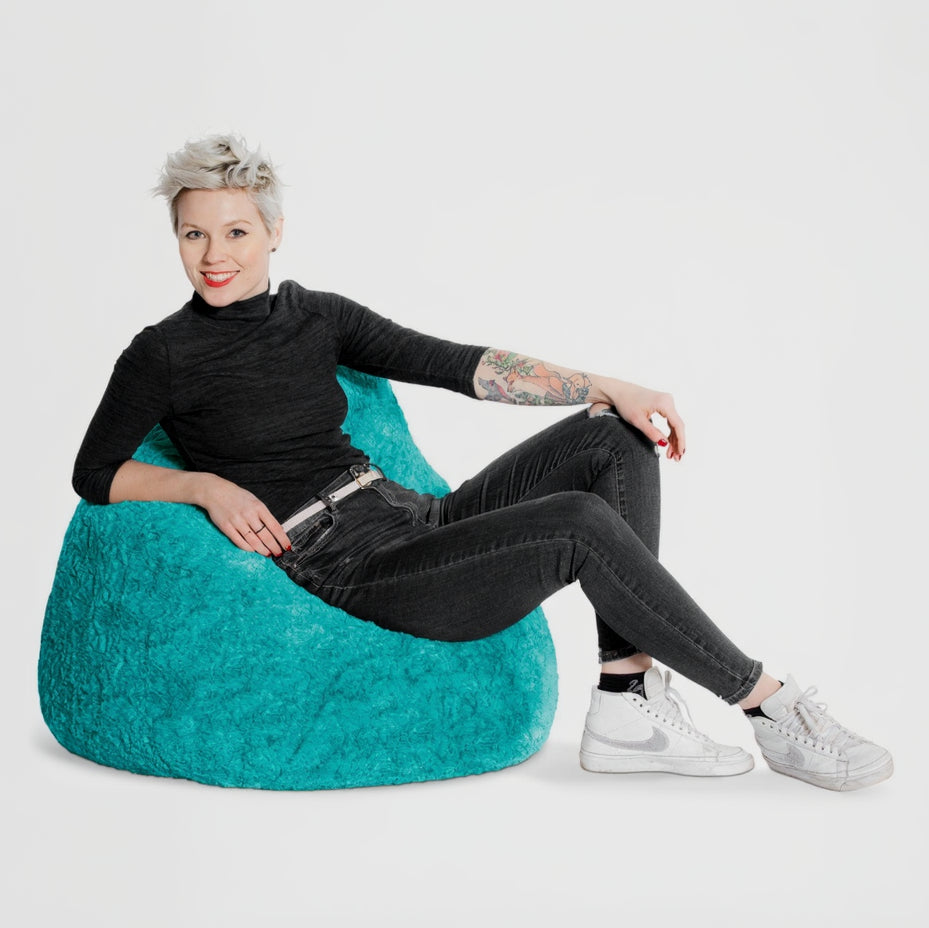 Person sitting on a teal bean bag chair against a white background