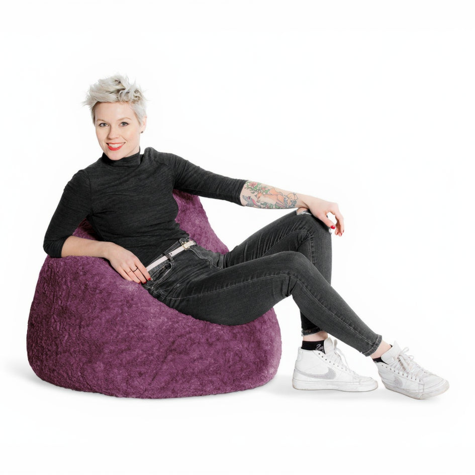 Person sitting on a purple bean bag chair against a white background