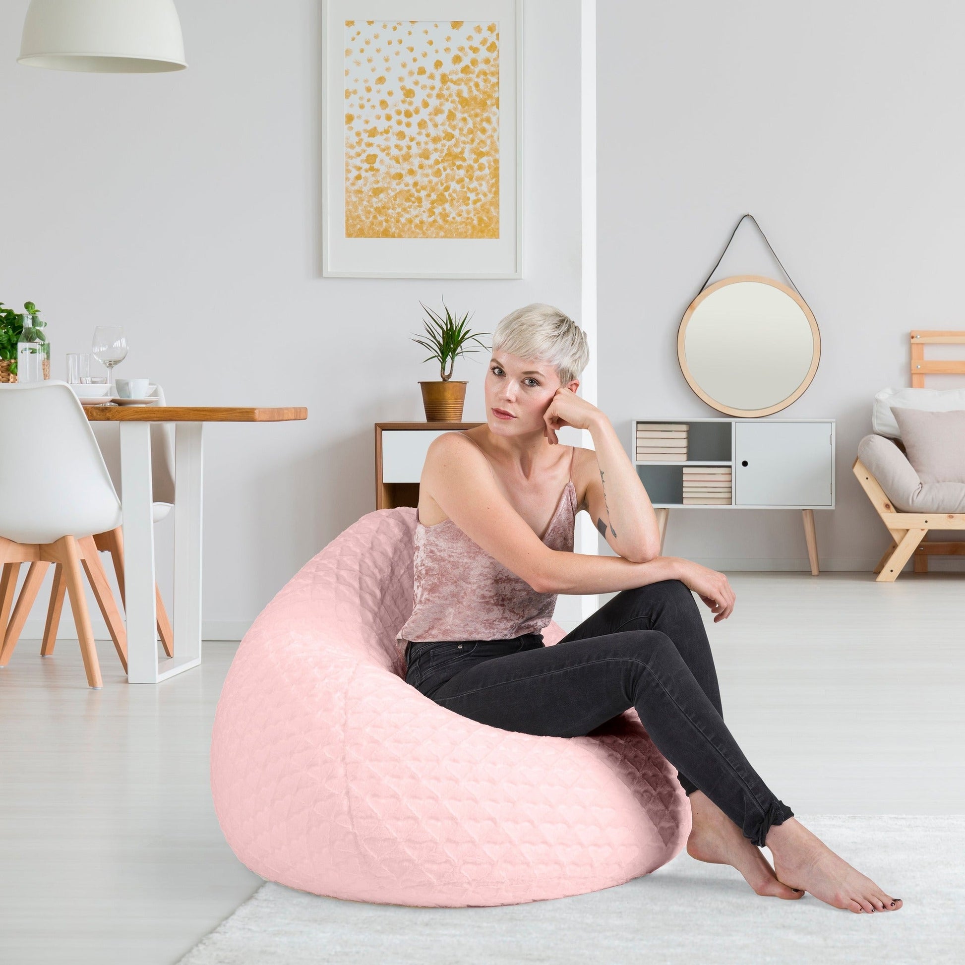 Woman sitting on a pink bean bag chair in a modern living room.