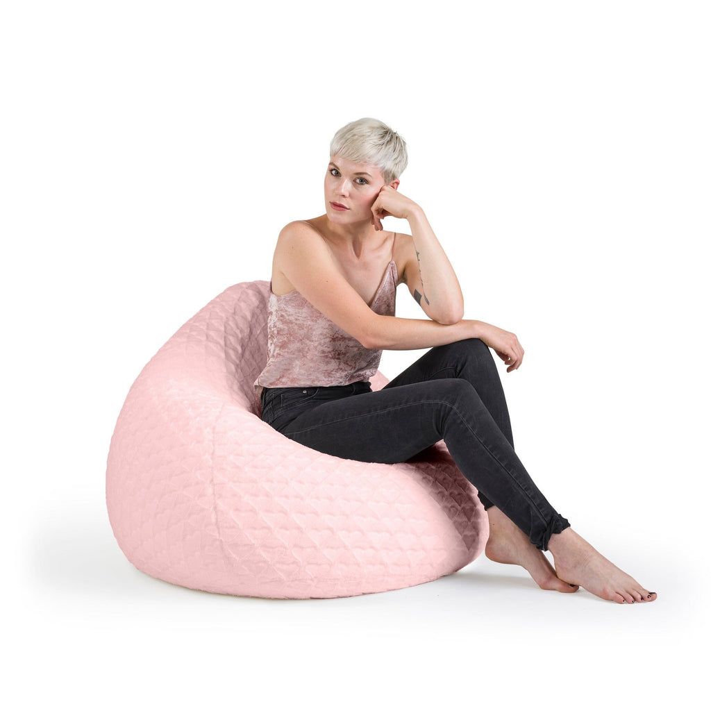 Woman sitting on a pink bean bag chair against a white background