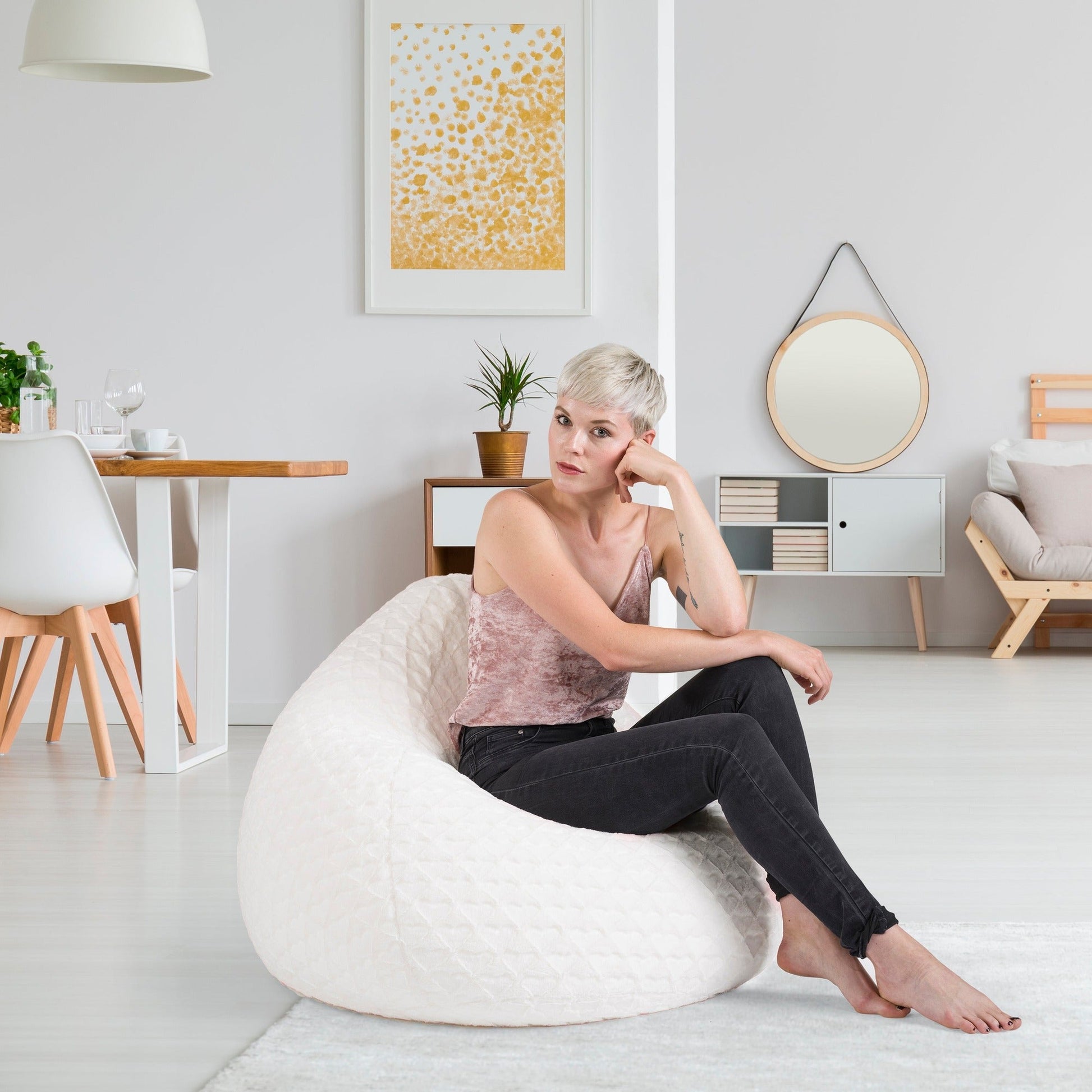 Woman sitting on a white bean bag chair in a modern living room.