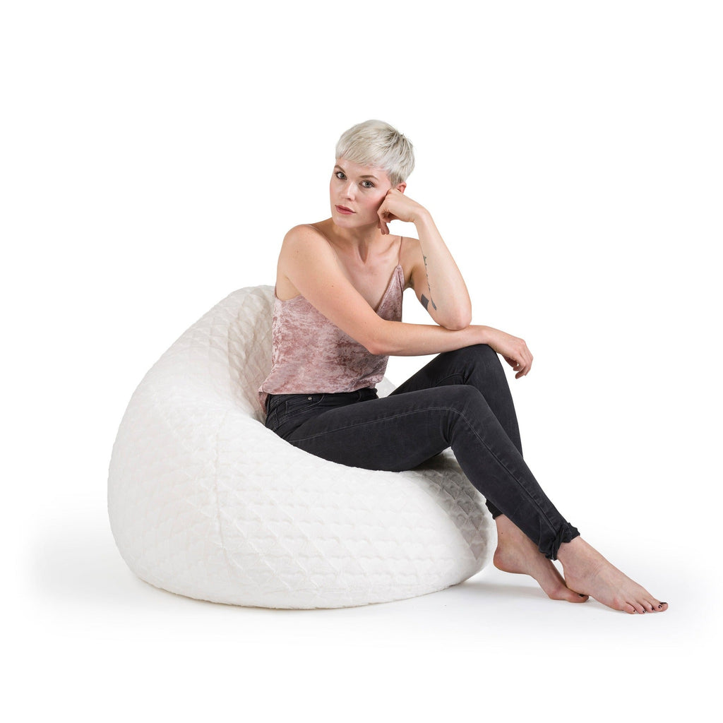 Woman sitting on a white bean bag chair against a white background