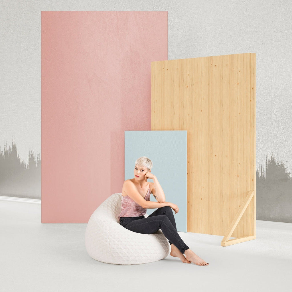 Woman sitting on a white bean bag chair between two colorful room dividers against a light gray background.