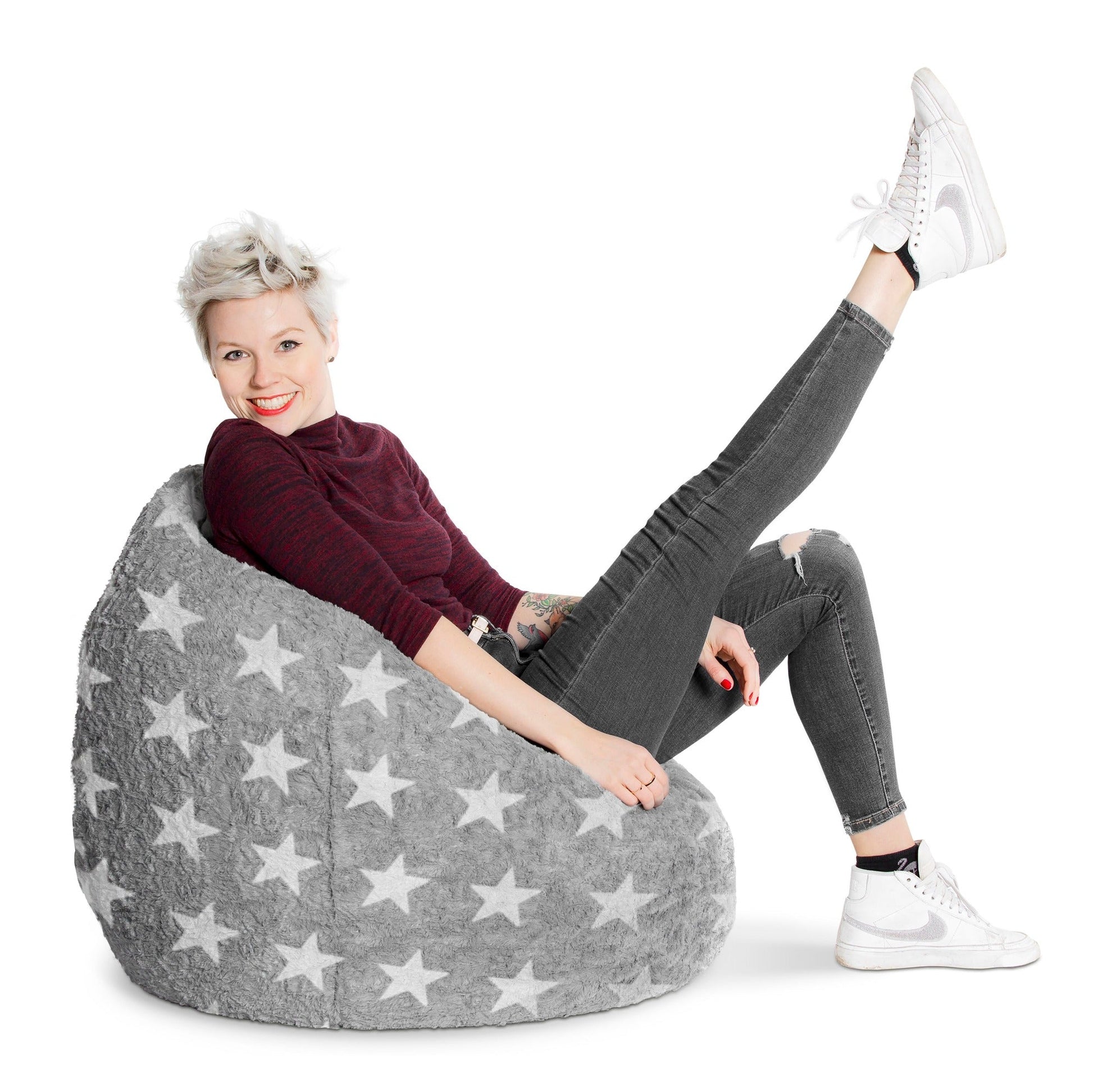 Person sitting on a gray bean bag chair with star patterns on a white background