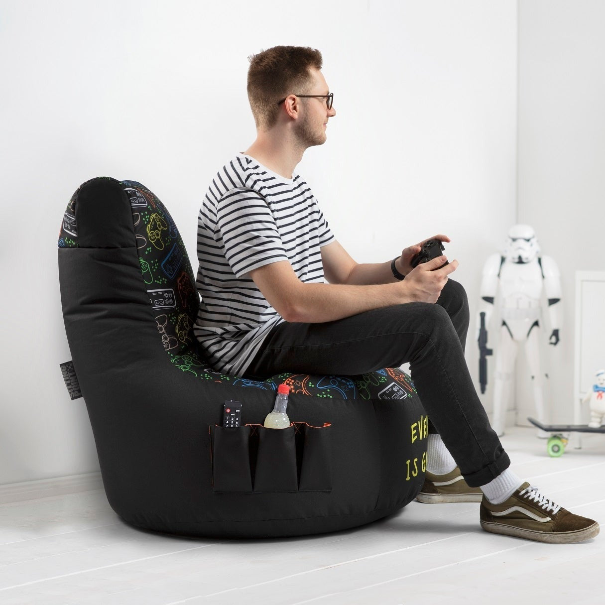 Man playing video games on a console in a modern living room with a bean bag chair.
