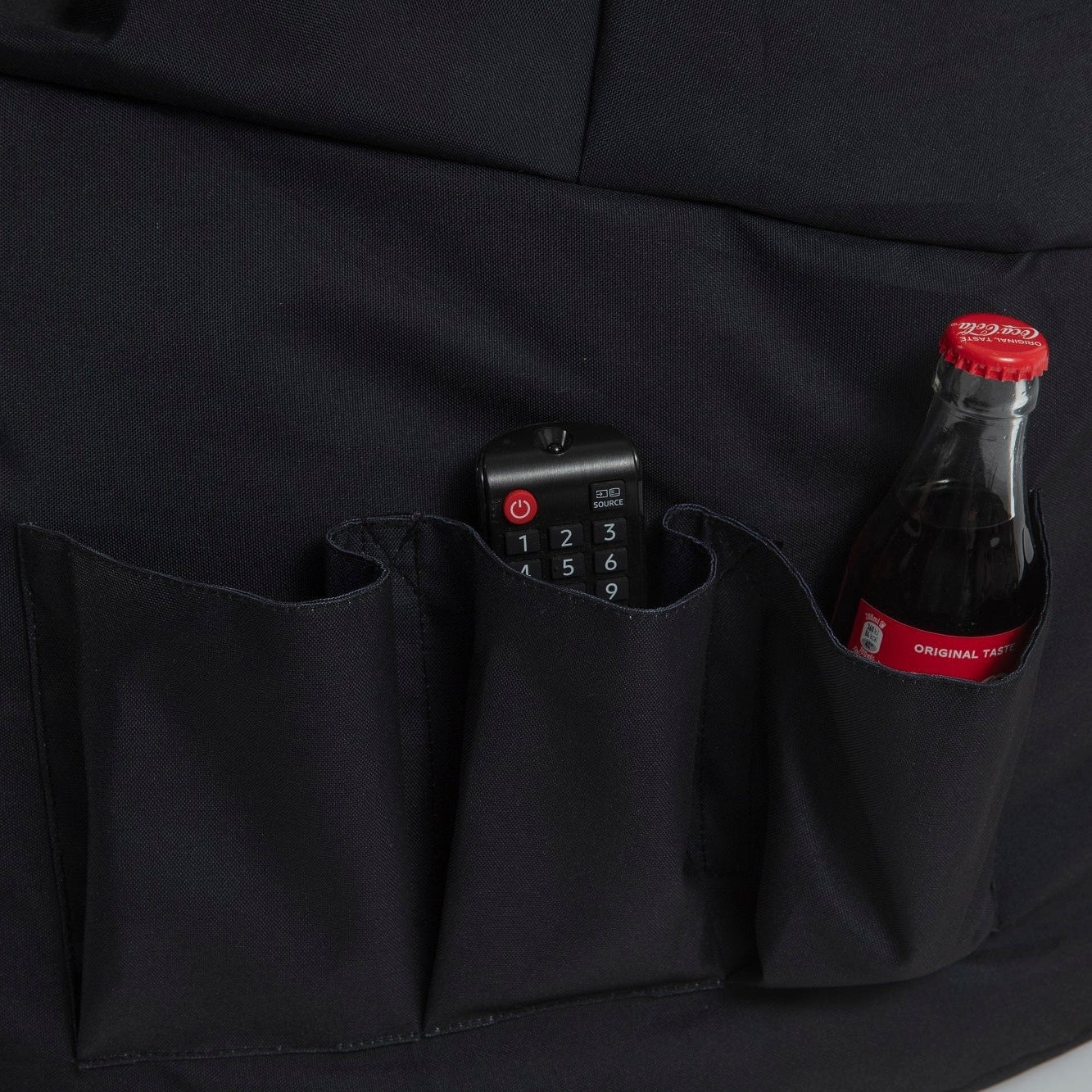 Black bag with a remote control and Coca-Cola bottle in a pocket