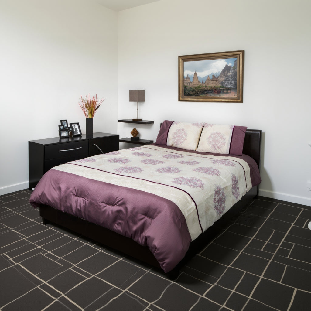 Bed with purple and white floral patterned bedding in a bedroom setting.