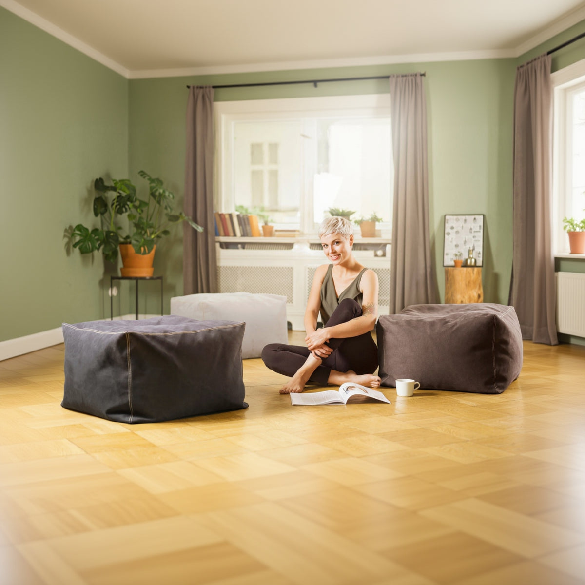 Woman sitting on a bean bag chair reading a book in a cozy living room.