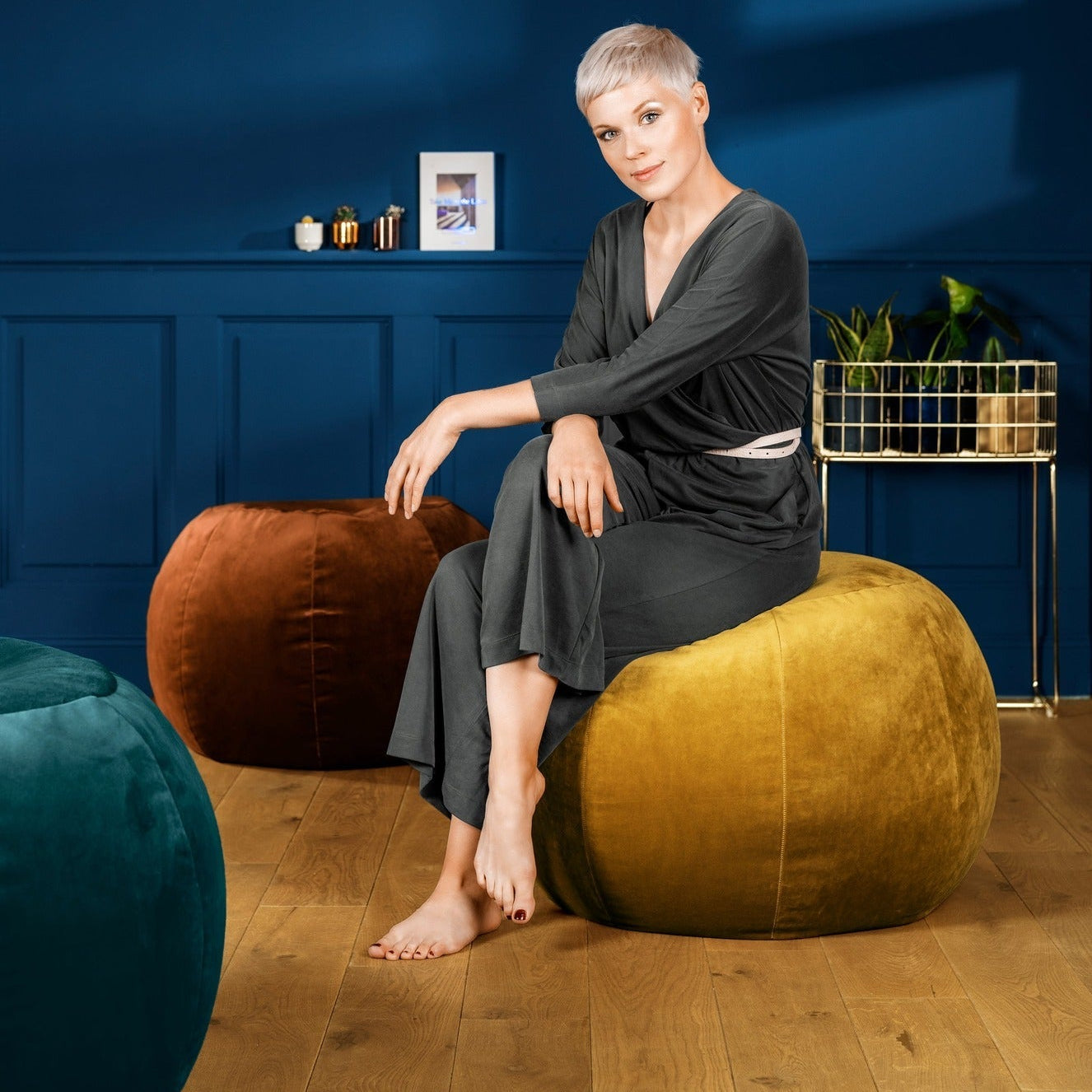 Woman sitting on a large yellow bean bag chair in a room with blue walls and wooden flooring.