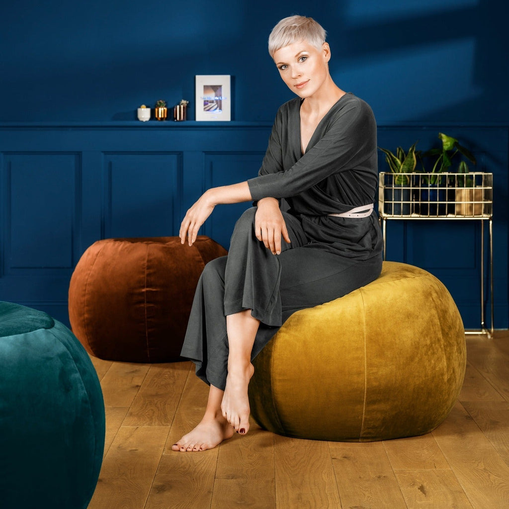 Woman sitting on a large yellow bean bag chair in a room with blue walls and wooden flooring.