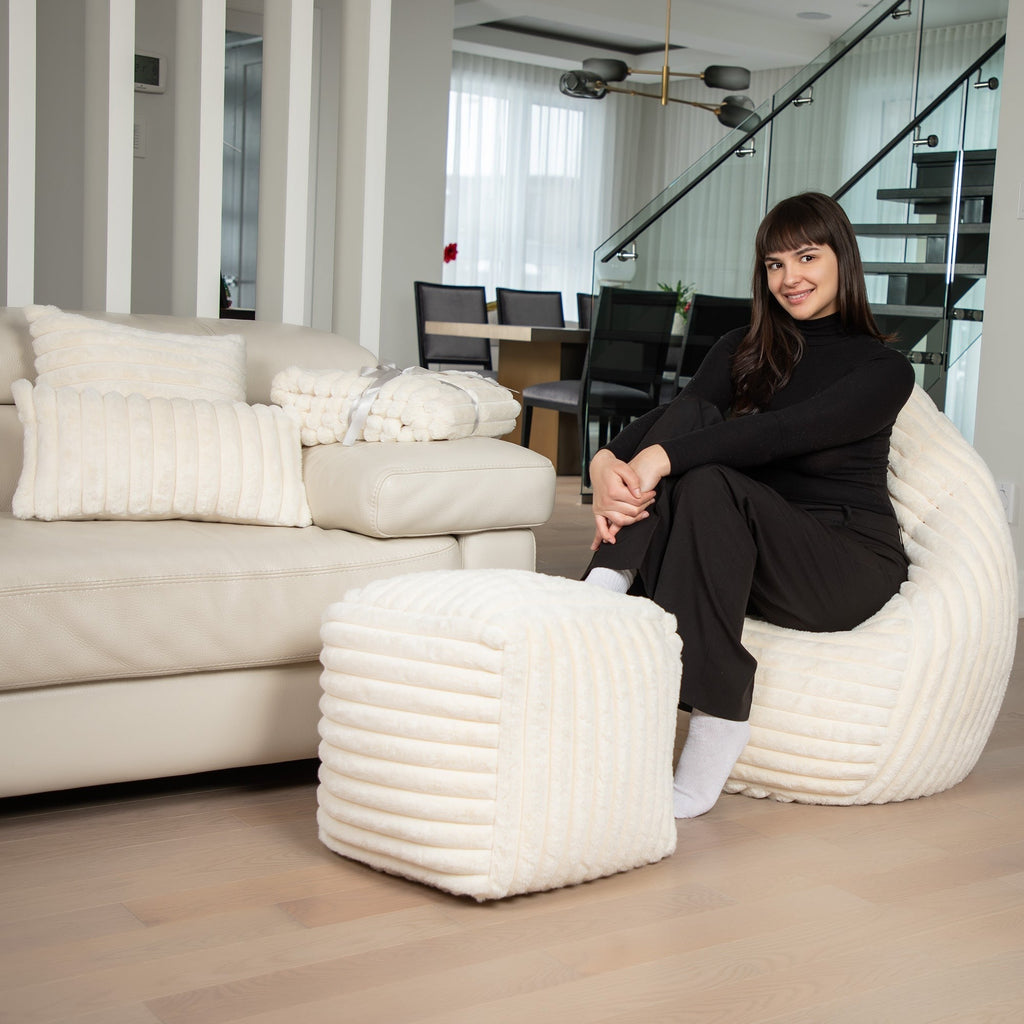 Woman sitting on a white bean bag chair in a modern living room.