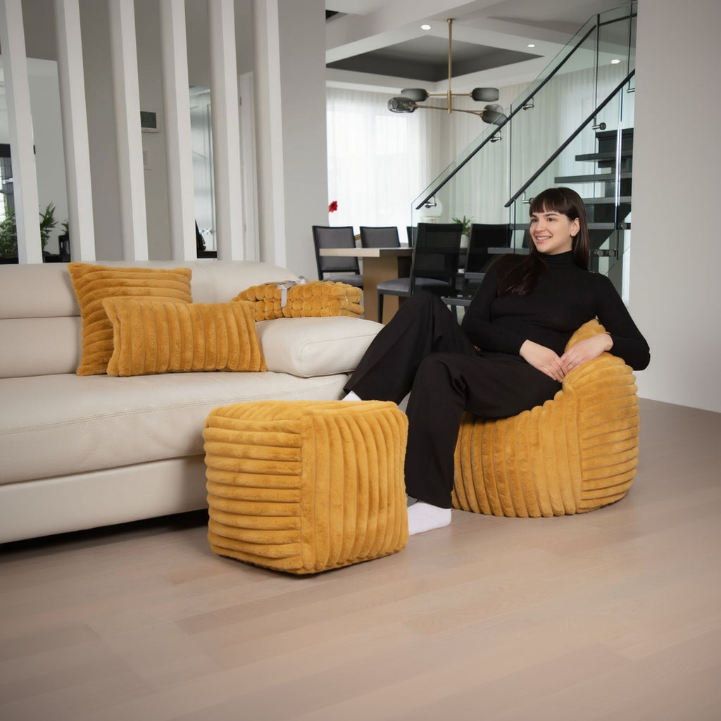 Woman sitting on a yellow textured chair in a modern living room.