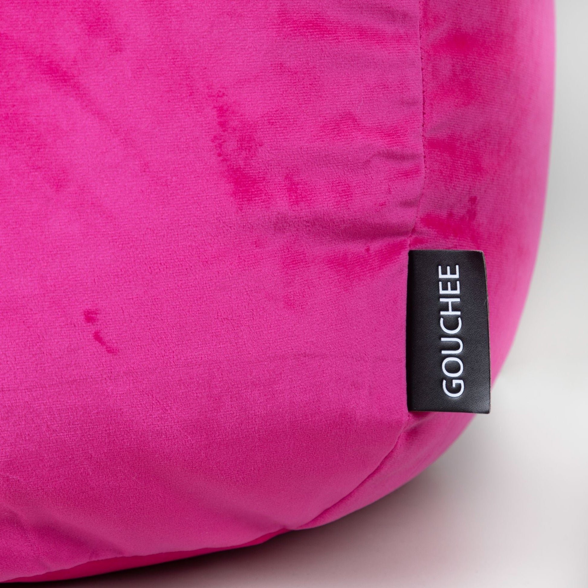 Close-up of a pink cushion with a 'Gouchee' label on a light background