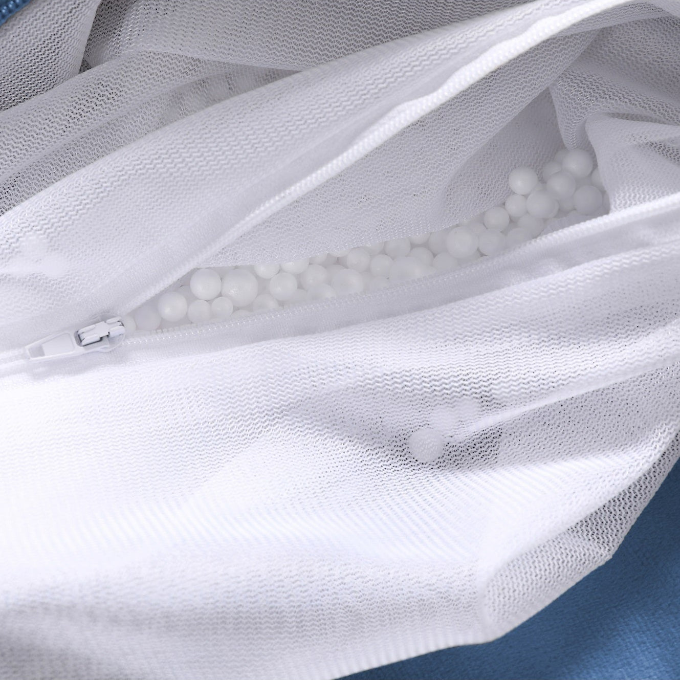 White mesh laundry bag with blue fabric in the background