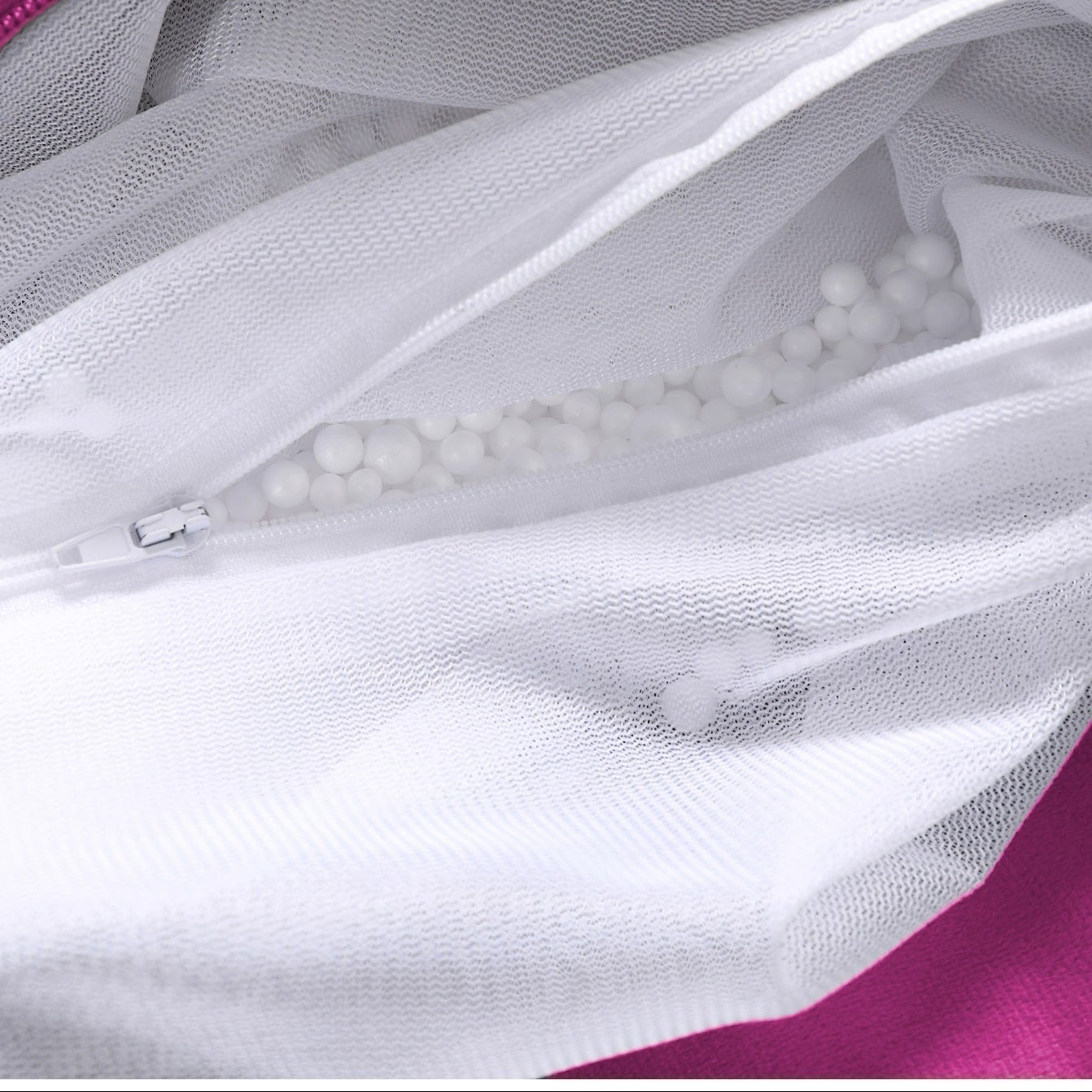 White mesh bag with a zipper on a pink background