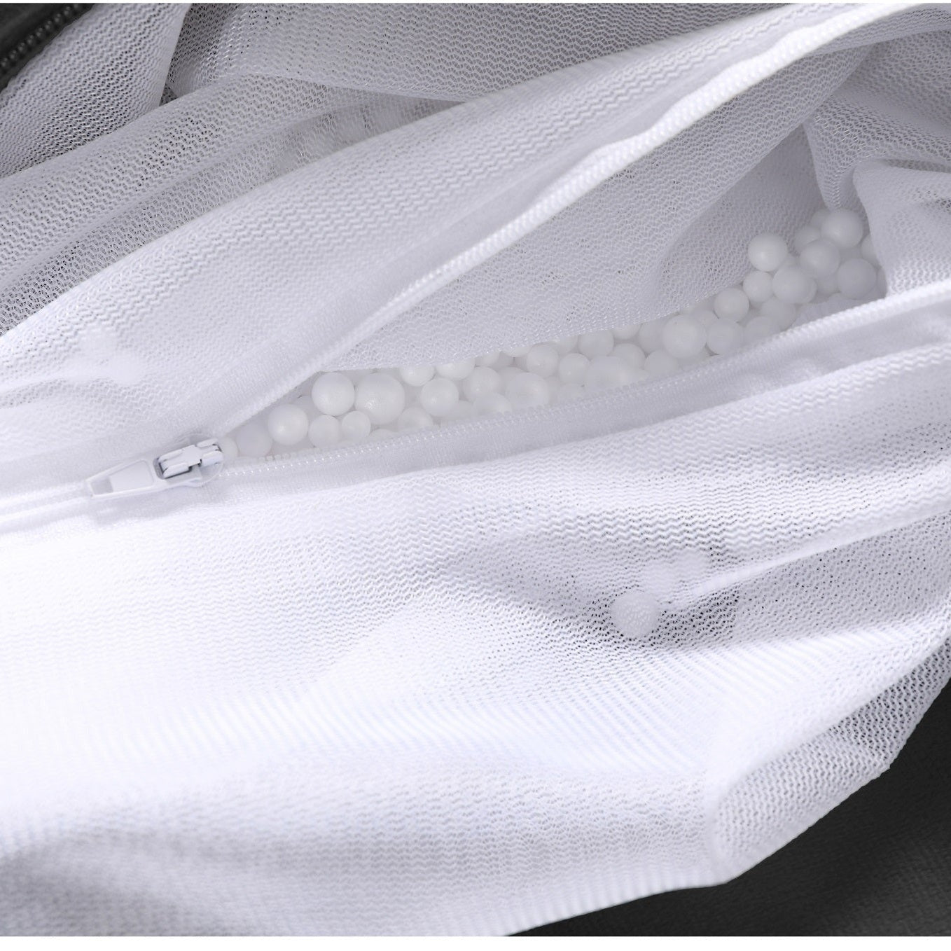 White mesh bag with a zipper containing white pearls on a dark background
