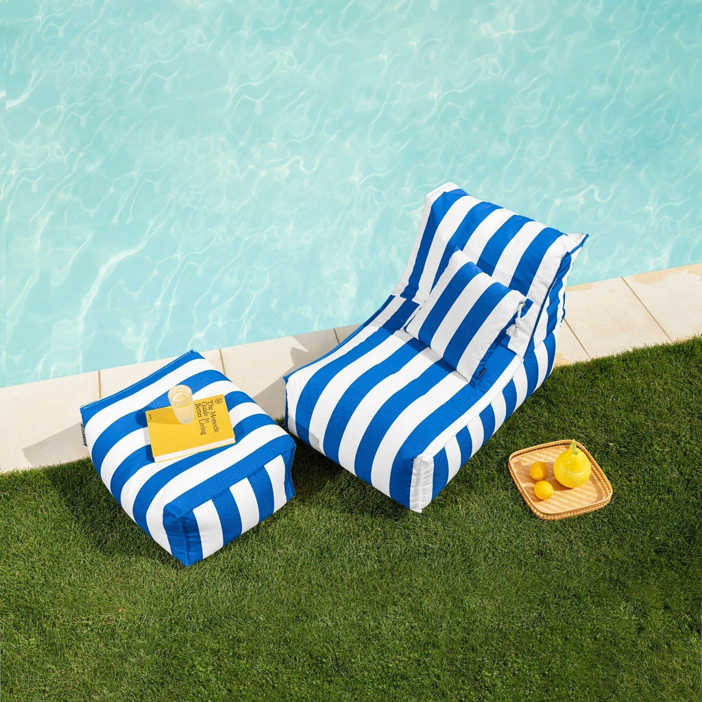 Blue and white striped inflatable lounge by a poolside with a small table and lemons.