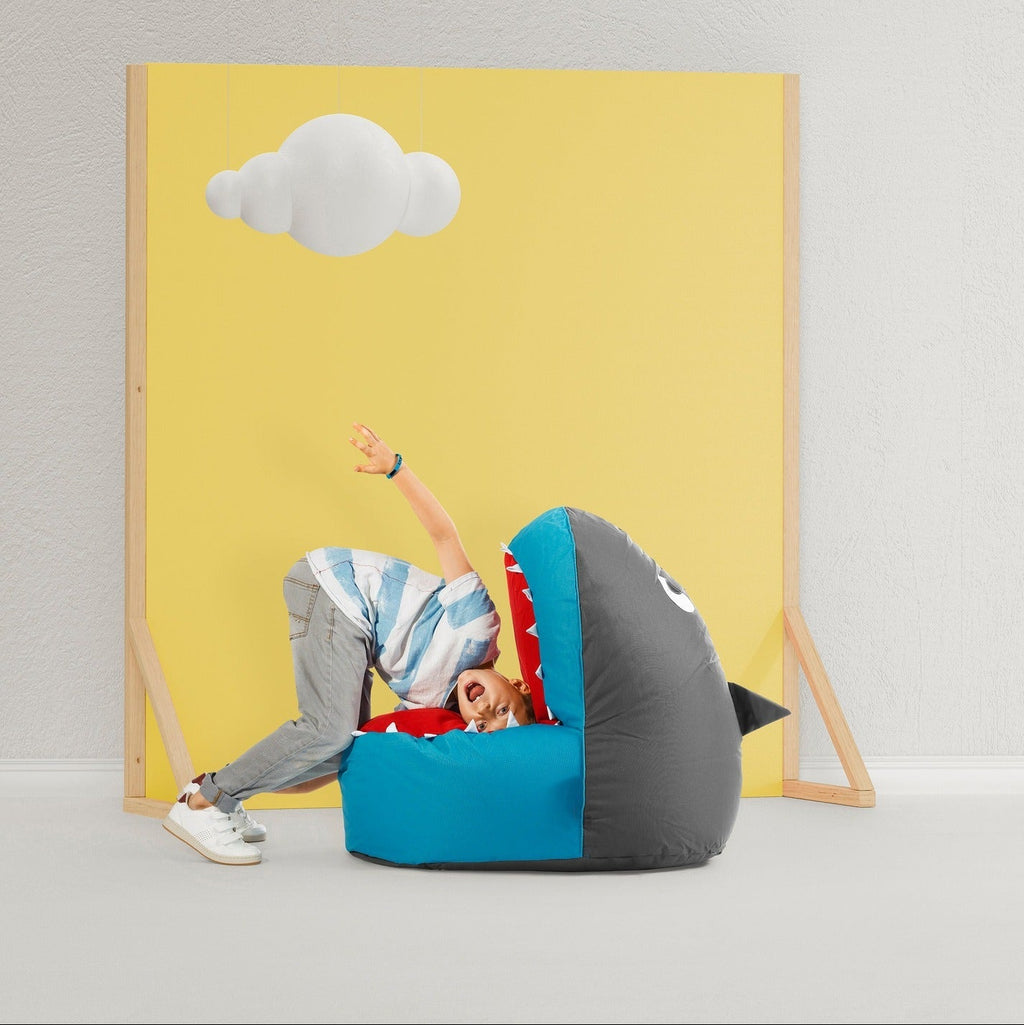 Person playing with a bean bag chair against a yellow wall with a cloud design.