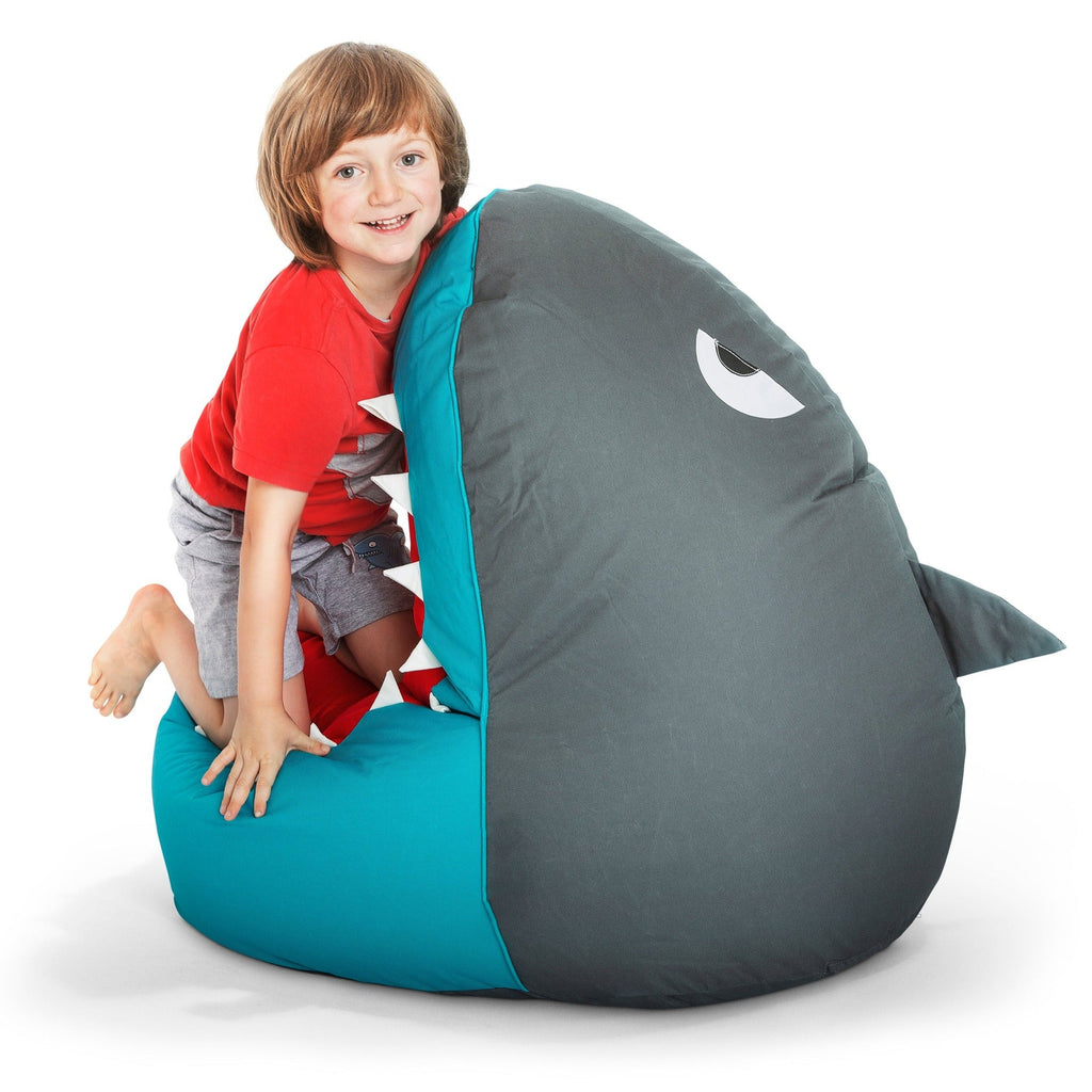 Child sitting on a shark-shaped bean bag chair with a white background