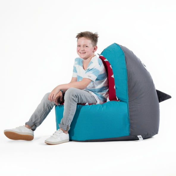 Child sitting on a shark-shaped bean bag chair with a white background
