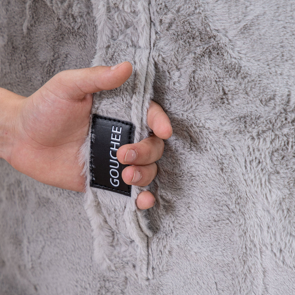 Hand holding a black card with 'Gouchee' branding against a textured gray fabric background