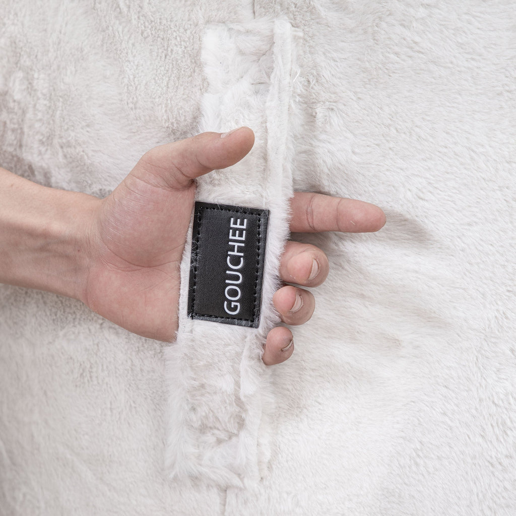 Hand holding a white textured fabric with 'Gouchee' label