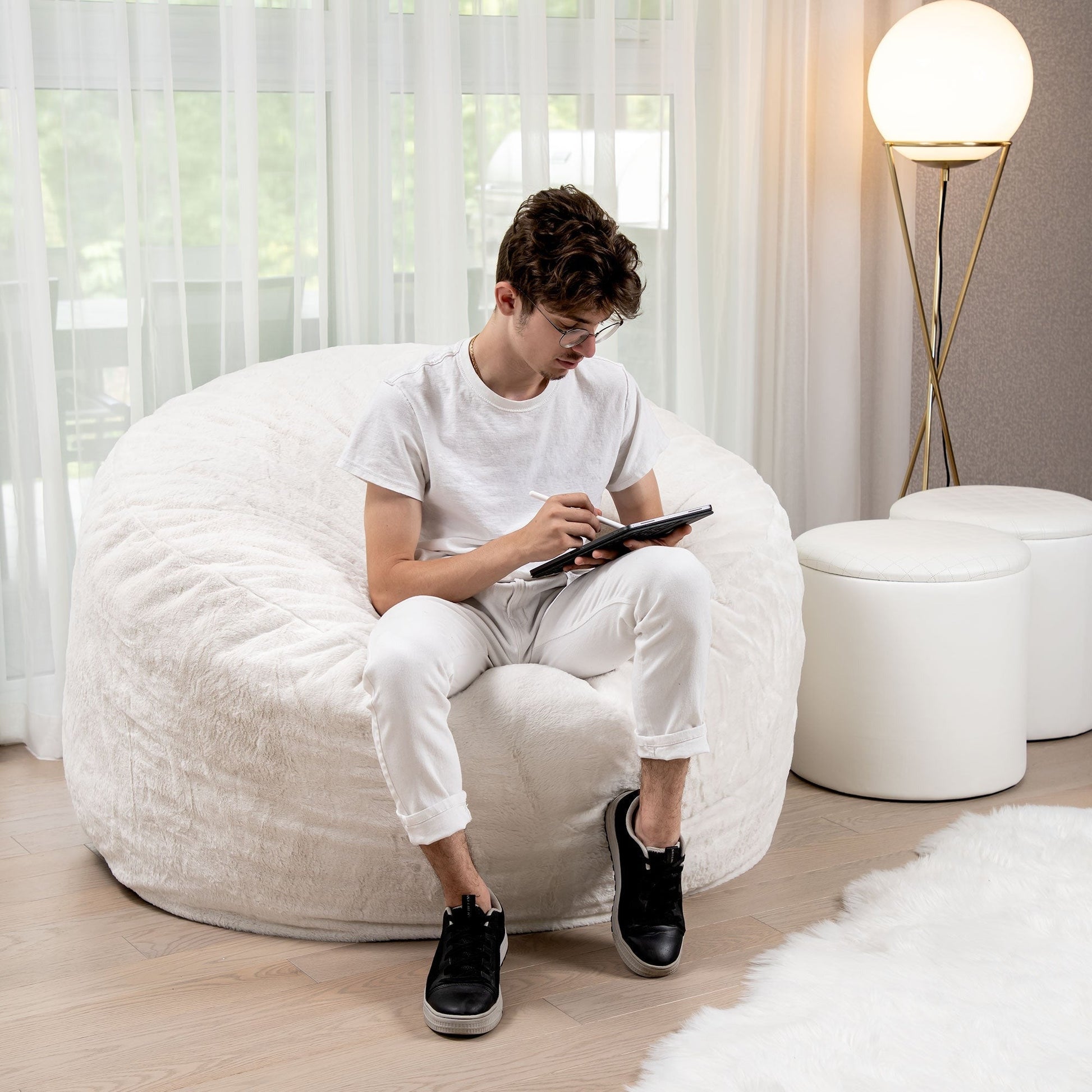 Person sitting on a white bean bag chair in a modern living room.