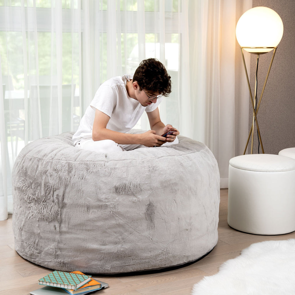 Person sitting on a textured ottoman in a modern living room.