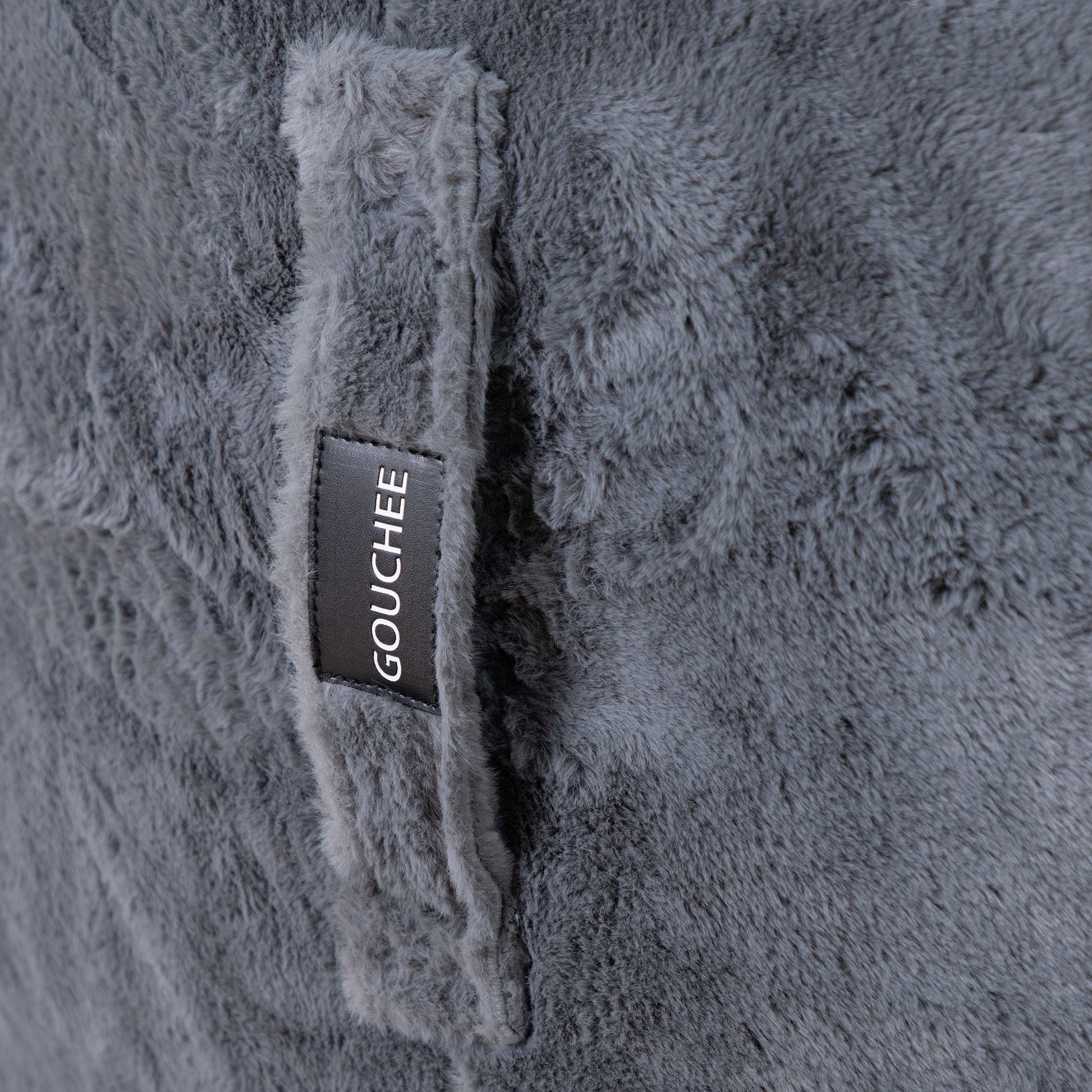 Close-up of a textured gray fabric with a brand label on a gray background