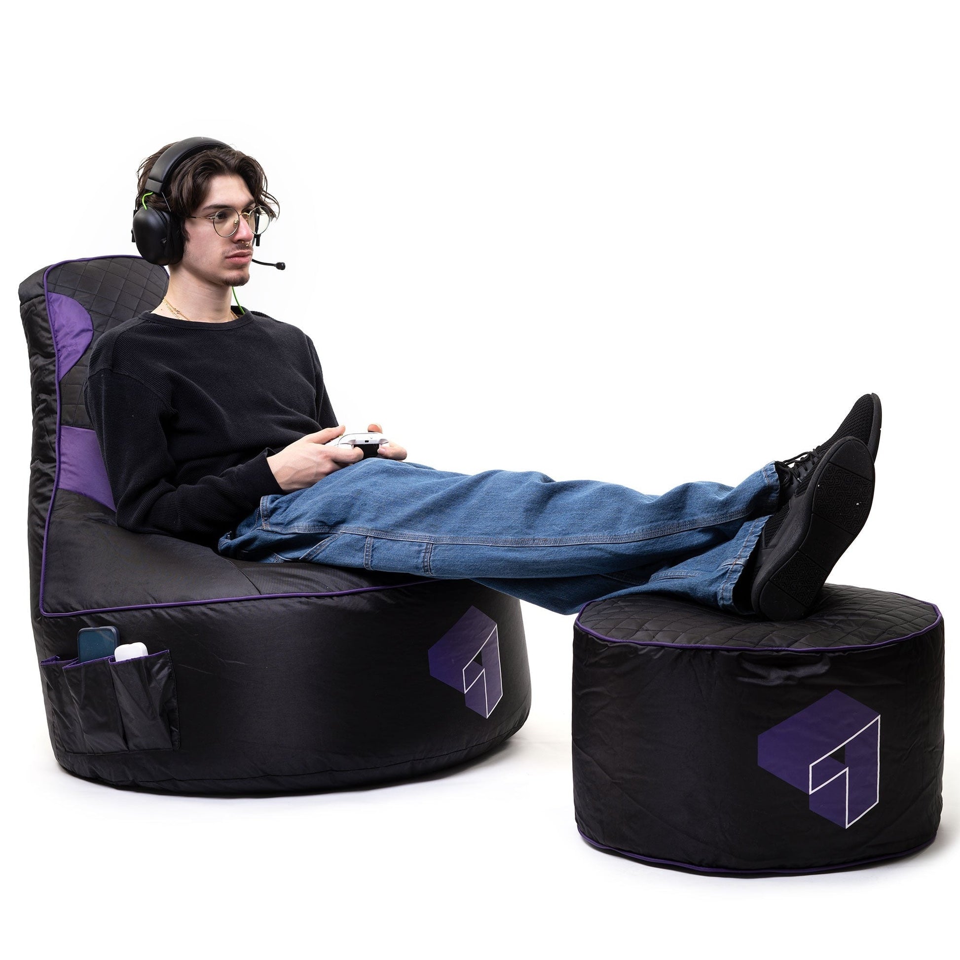 Person sitting on a black and purple gaming chair with a small ottoman.