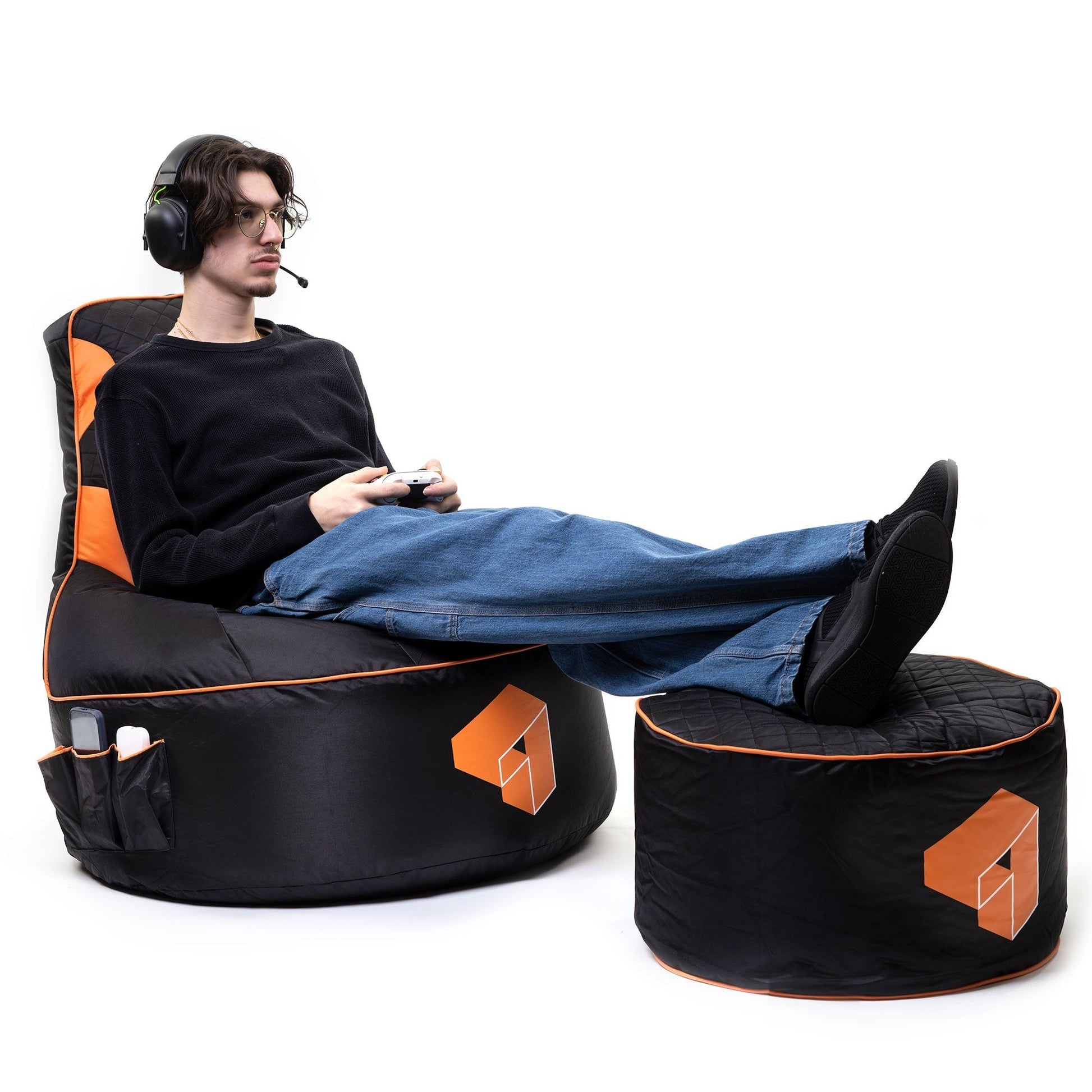 Person sitting on a black and orange gaming chair with a small ottoman.