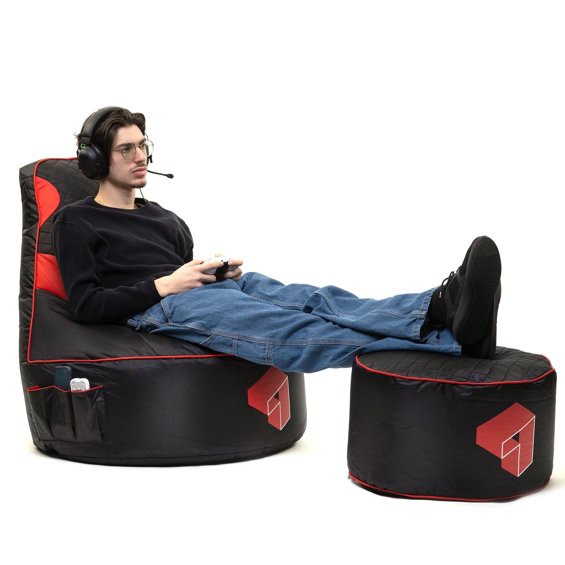 Person lounging on a black and red gaming chair with a small ottoman.
