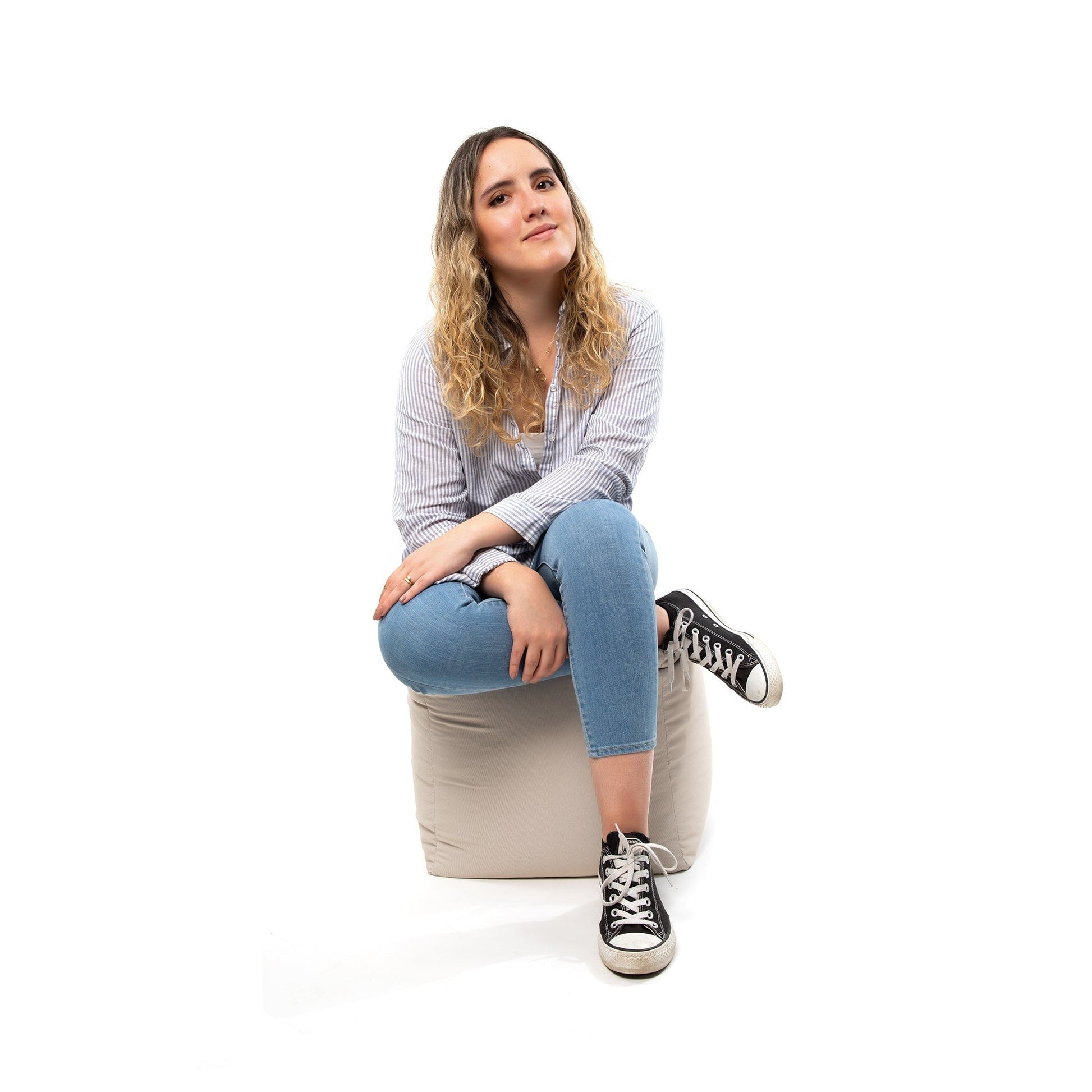 Woman sitting on a cube stool against a white background