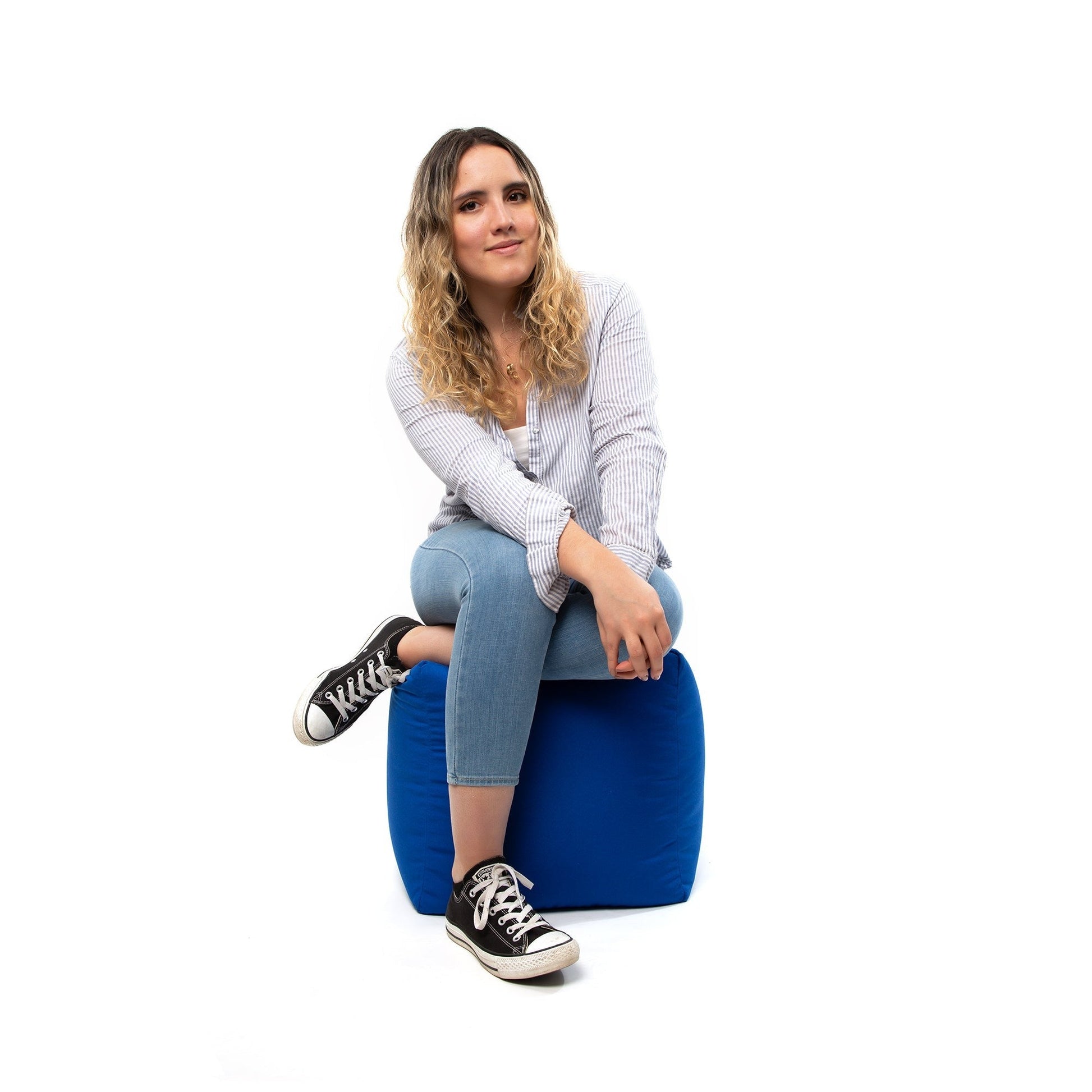 Woman sitting on a blue bean bag chair against a white background