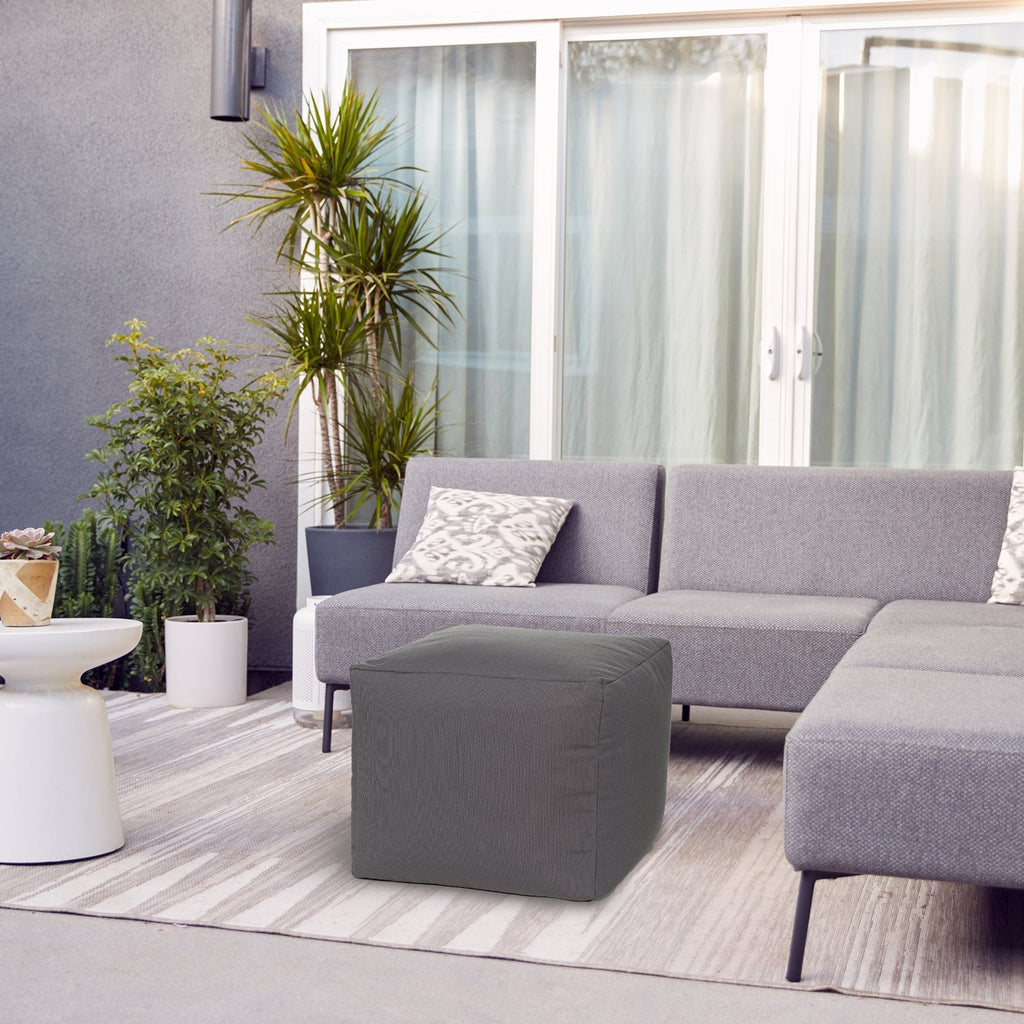 Gray sectional sofa with a cube ottoman in a modern living room setting.